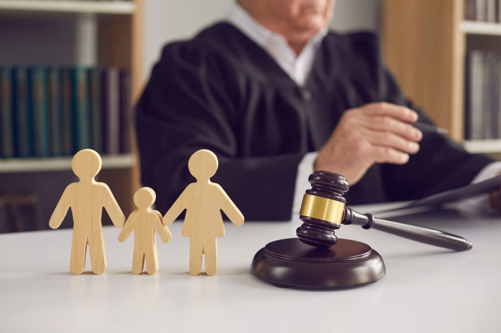 Gavel on sound block and small family member figurines on judge's table in courtroom