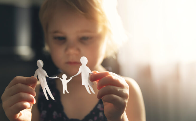 little girl with paper family in hands. concept of divorce, custody and child abuse